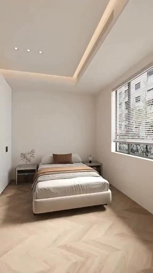 Minimalist bedroom with a low white bed, white walls, and light wood floors.