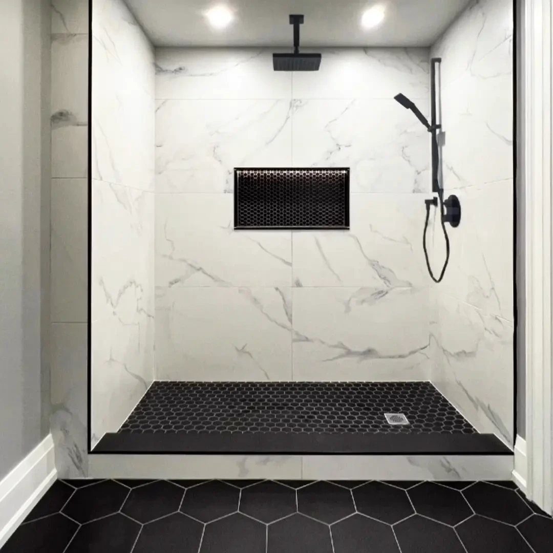 Black hexagon tile floor and shower base in a white marble bathroom.