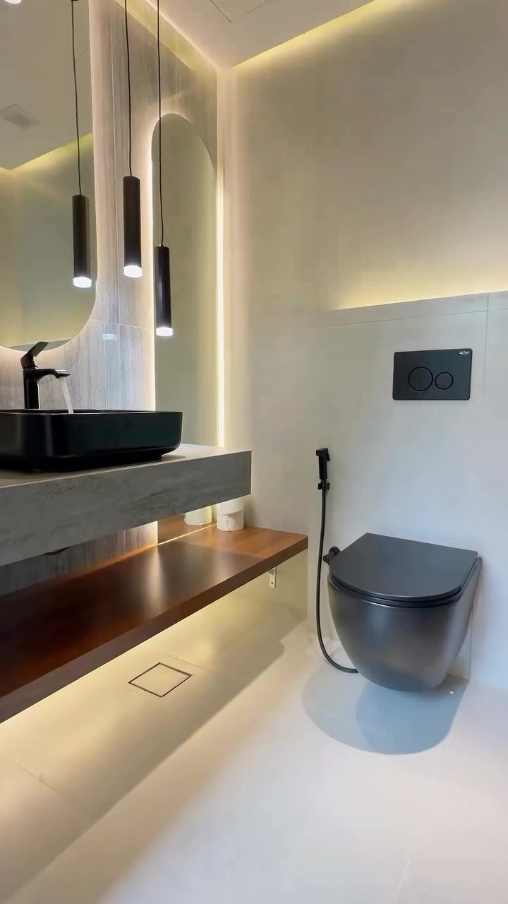 Modern bathroom with black sink and toilet against white walls and warm lighting.