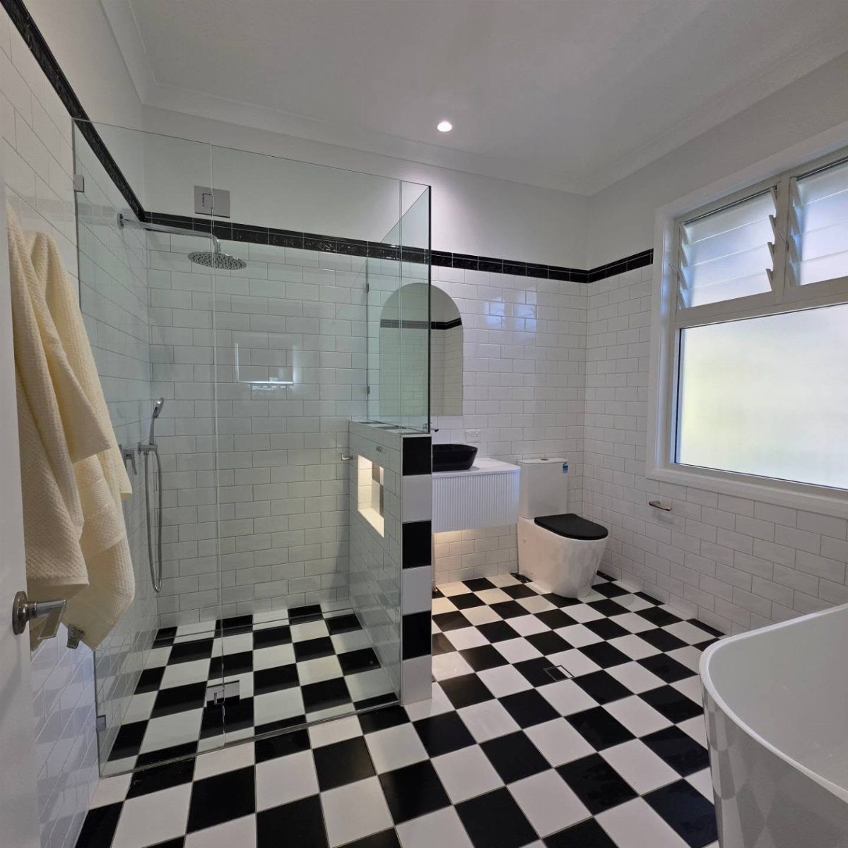 Checkerboard black and white tiled floor in a modern white subway tile bathroom.
