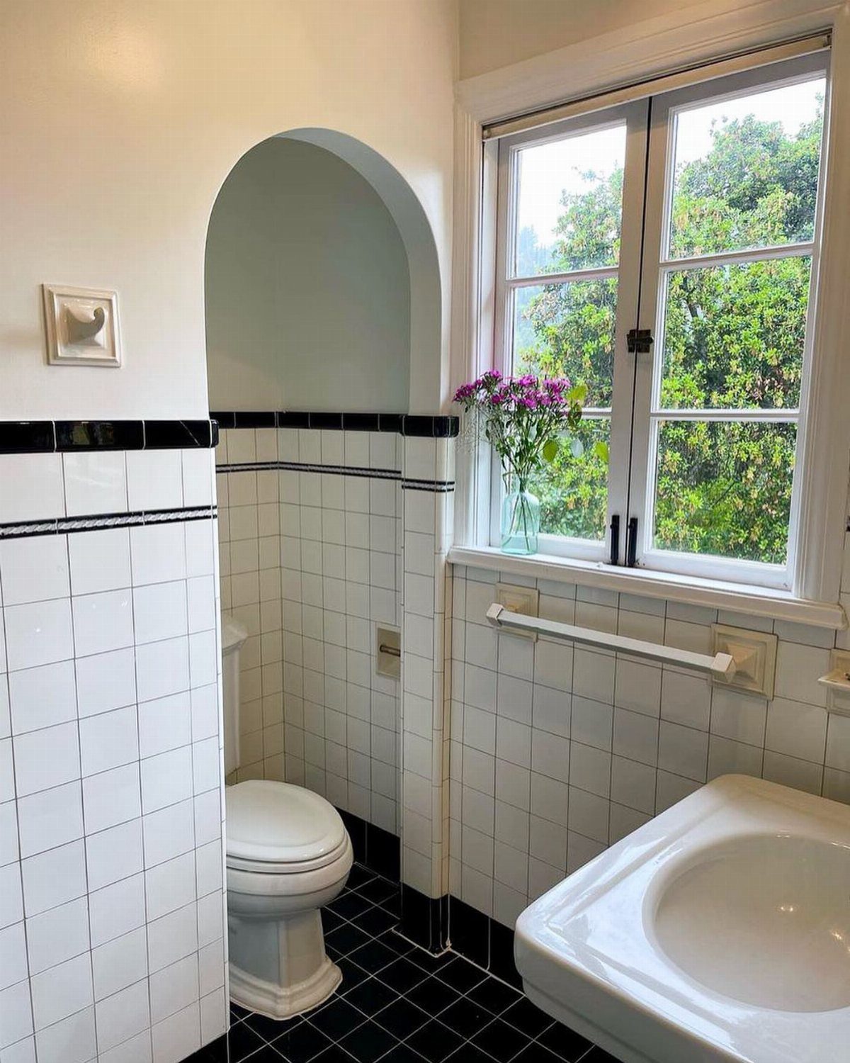 Bathroom with white square wall tiles, black borders, and black tiled flooring.