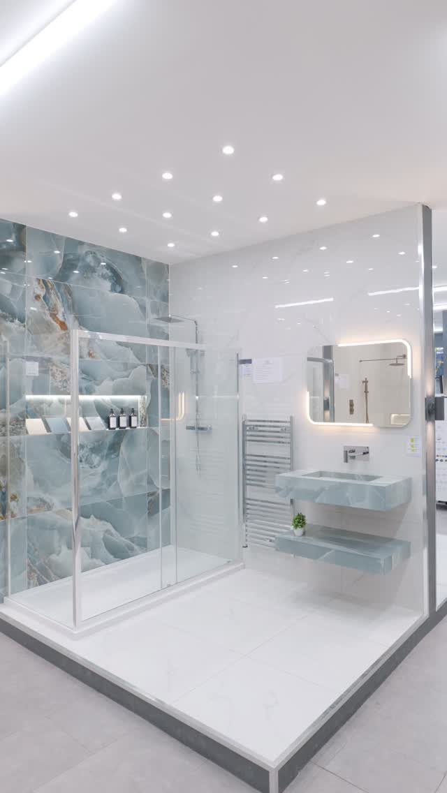 Modern bathroom with blue marbled shower tiles and a matching stone floating sink.