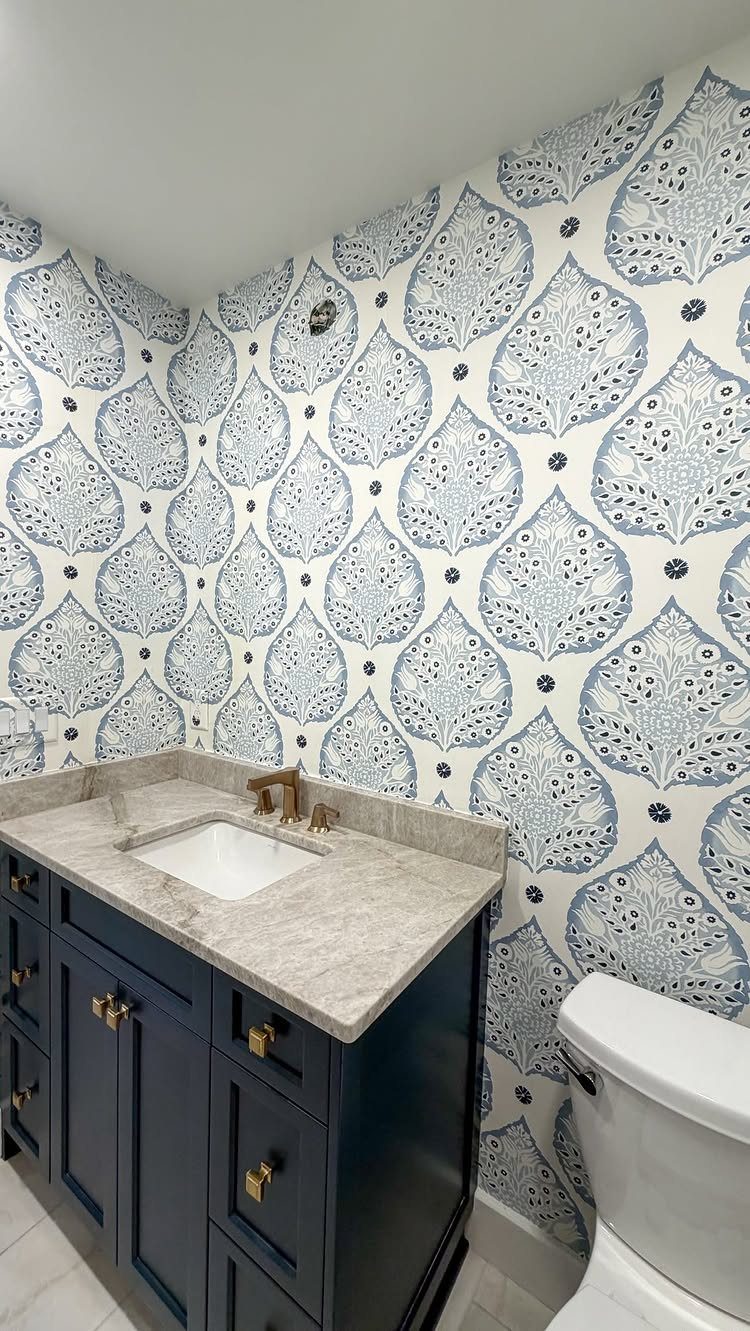 Blue and white patterned wallpaper in a bathroom with a navy blue vanity.