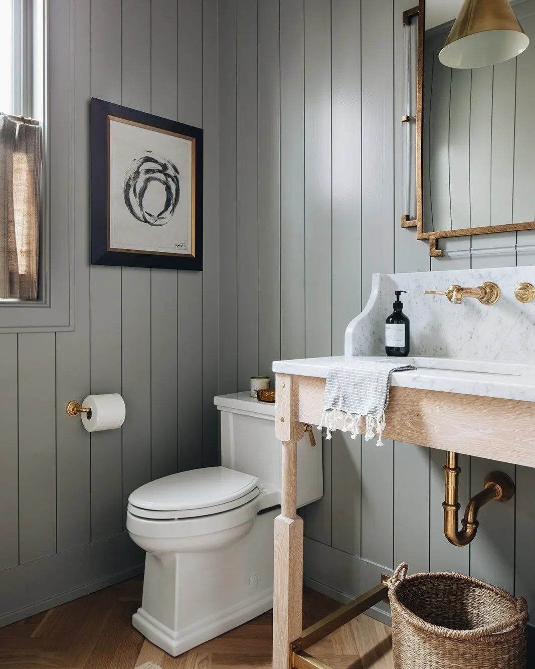Light grey shiplap walls in a bathroom with a marble vanity and gold fixtures