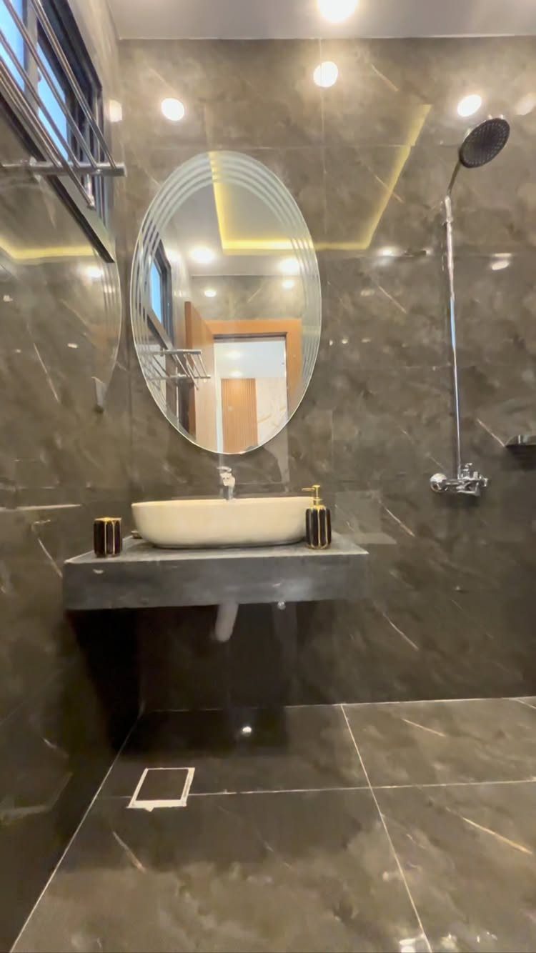 Dark grey marble bathroom with oval mirror and white vessel sink