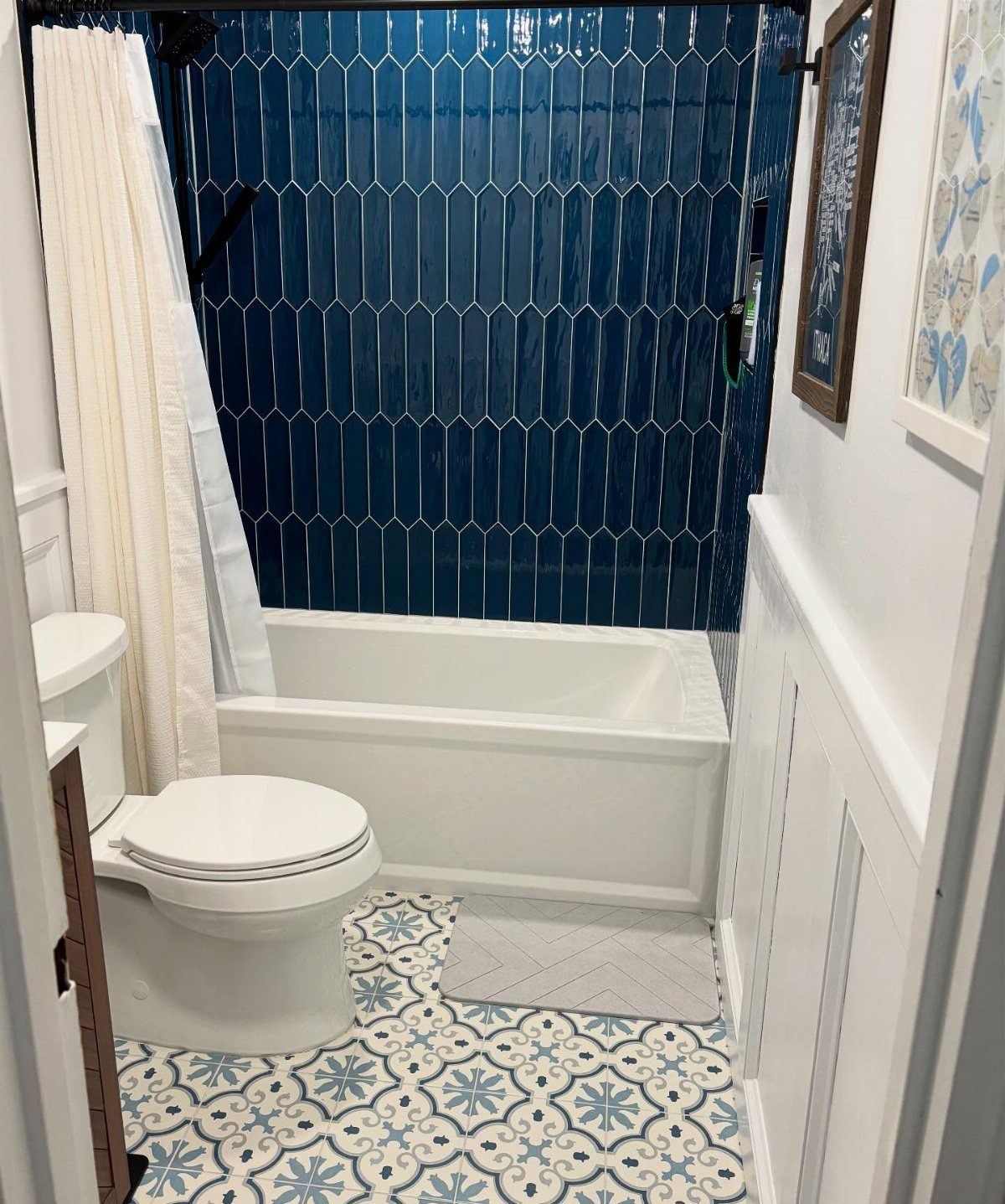 Navy blue picket tiles on a bathroom wall above a white bathtub.