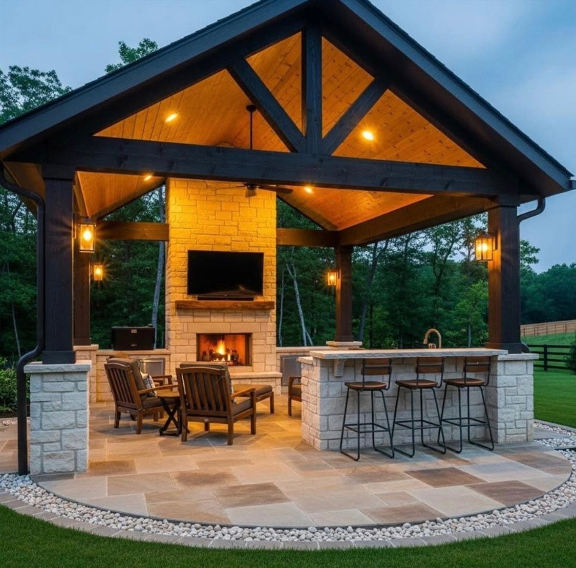 Outdoor pavilion with stone fireplace, bar, and patio overlooking a green lawn