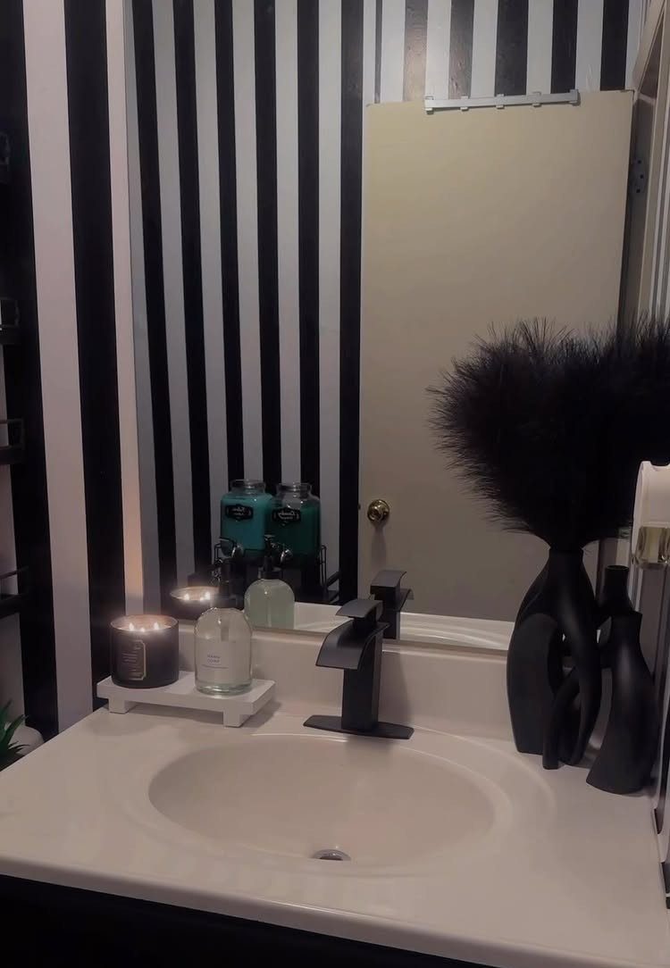 Black and white striped wallpaper in a bathroom with a white sink.