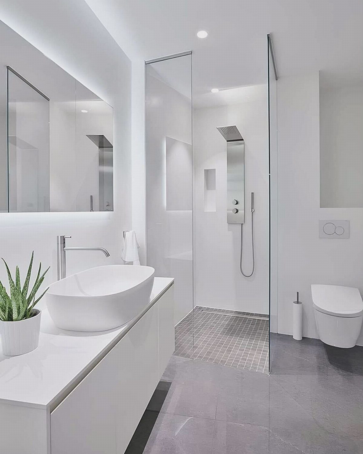 Modern white bathroom with vessel sink, glass shower, and small potted plant.