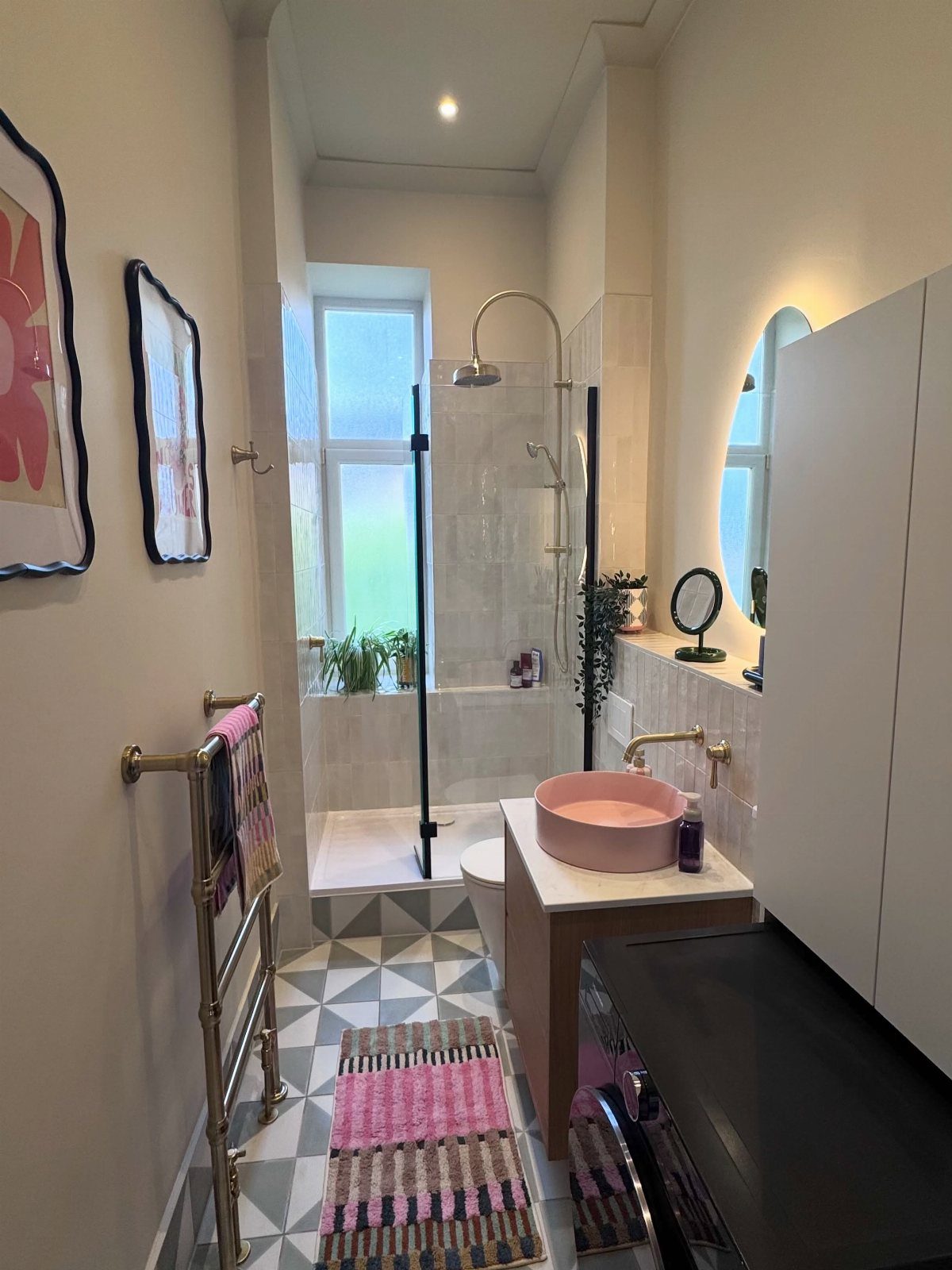 Pink vessel sink and gold fixtures in a white bathroom with geometric tiles.