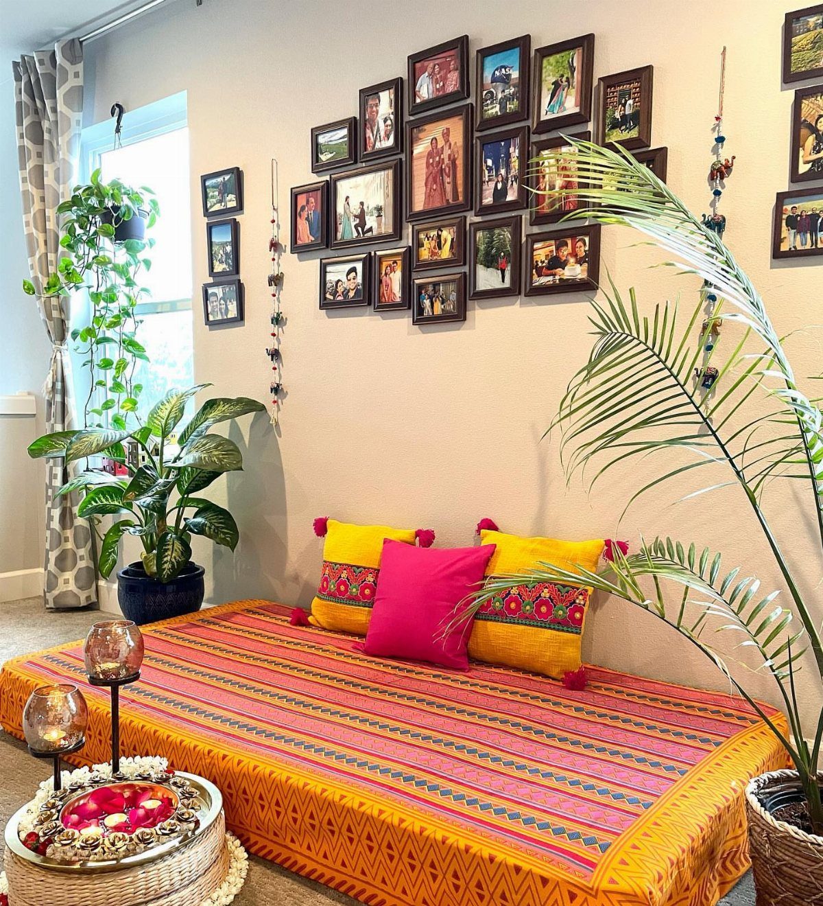 Colorful daybed with striped orange cover and gallery wall of framed photos.