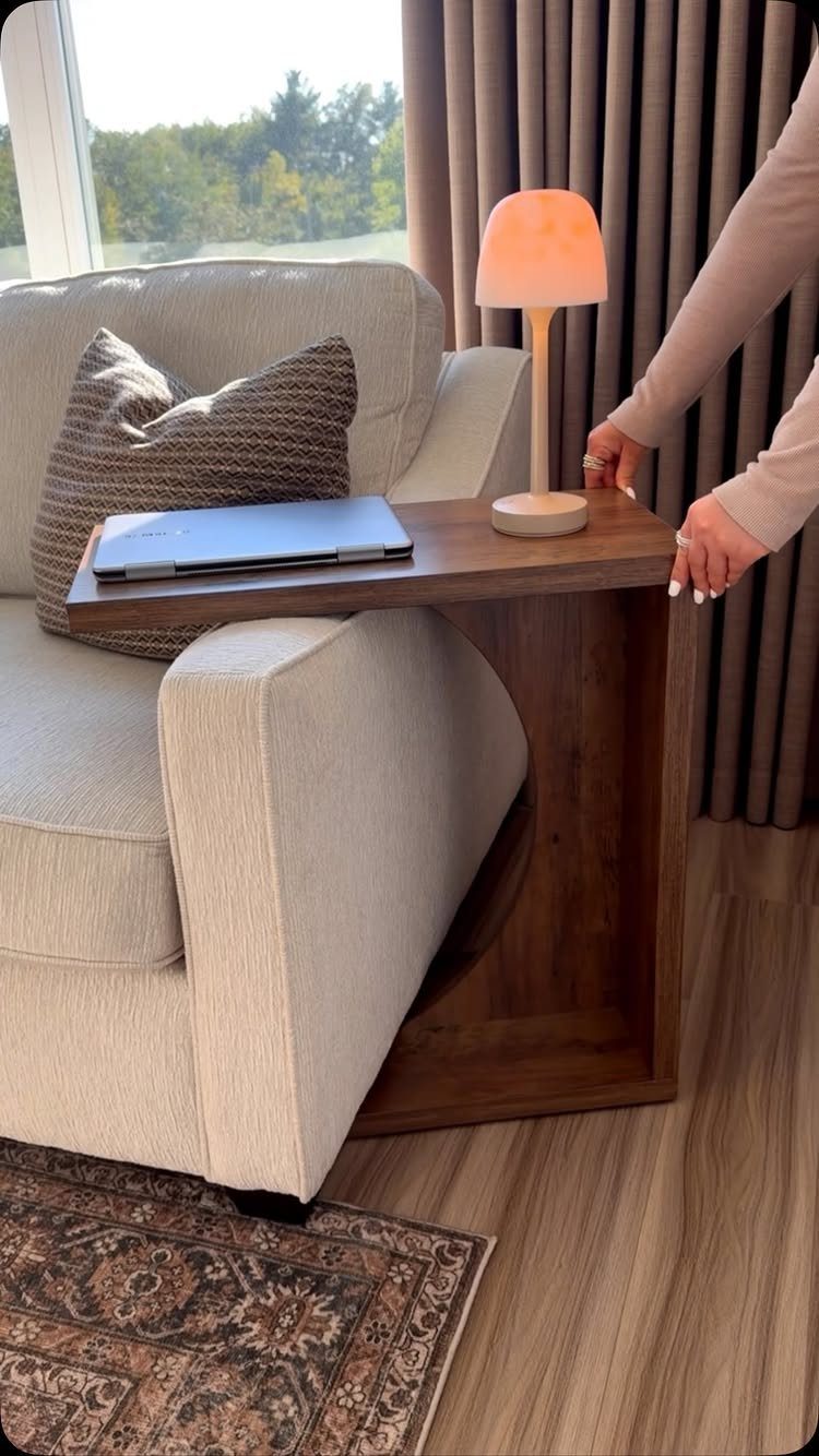 Small wooden C-shaped side table with a lamp and laptop next to a sofa