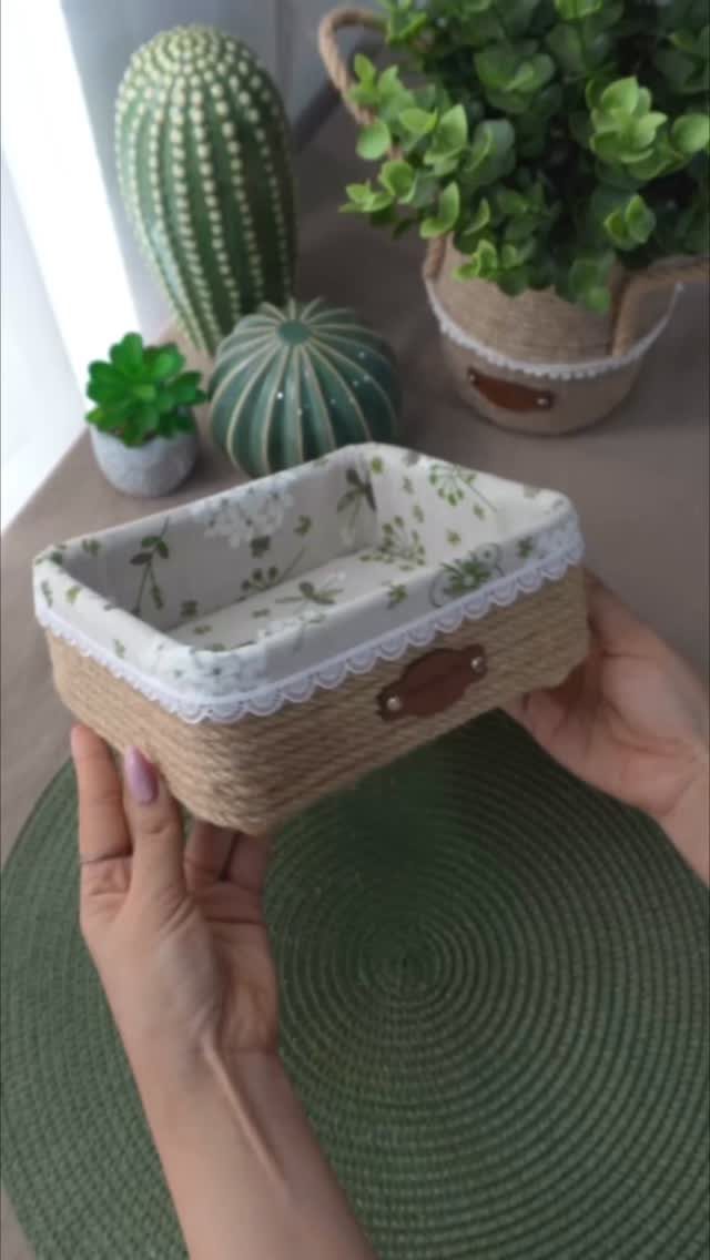 Woven wicker storage basket with fabric lining held by two hands near cacti.