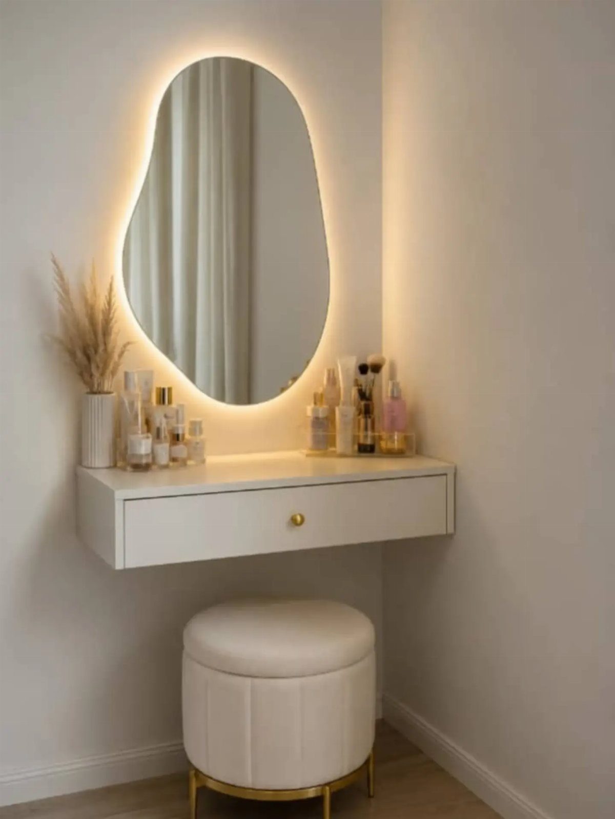 White floating vanity with a backlit organic mirror and a round white ottoman.