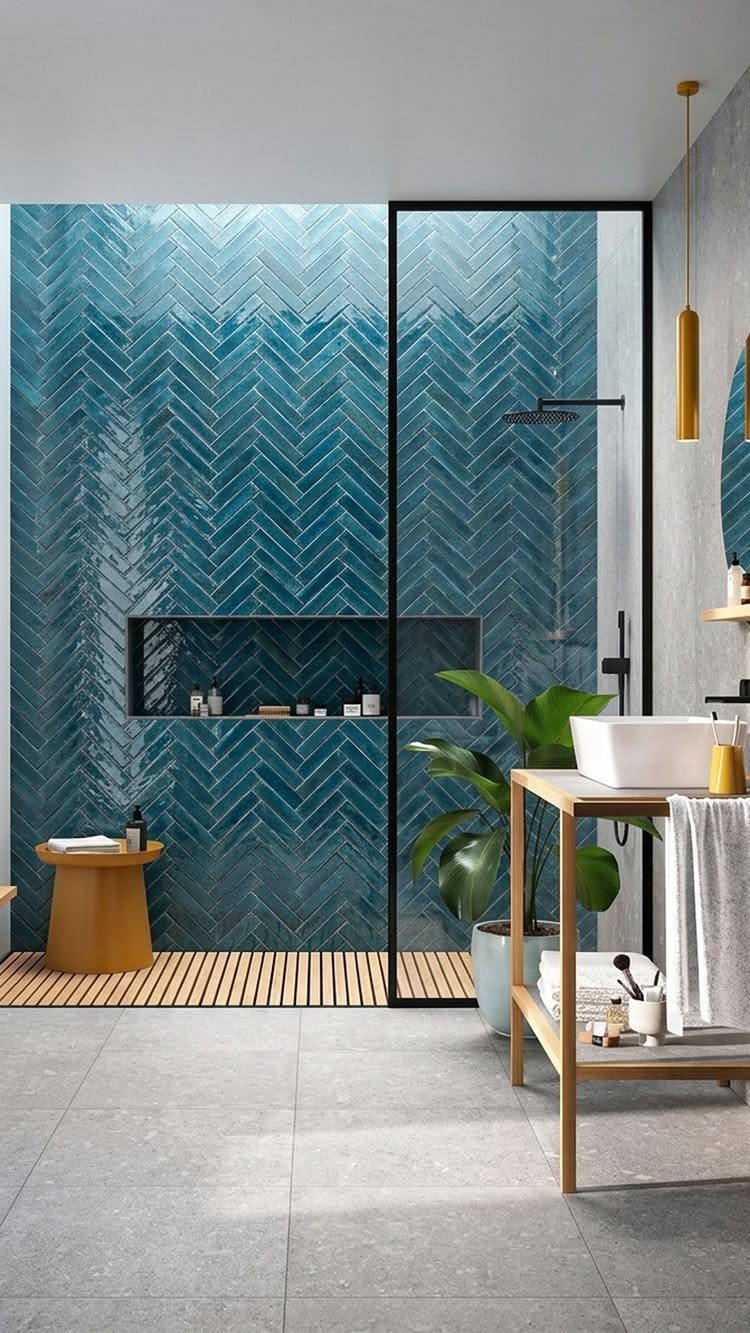 Dark blue herringbone tiles on a bathroom wall with a glass shower enclosure.