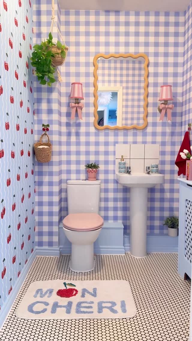 Blue and white gingham wallpapered bathroom with cherry patterns and pink accents.