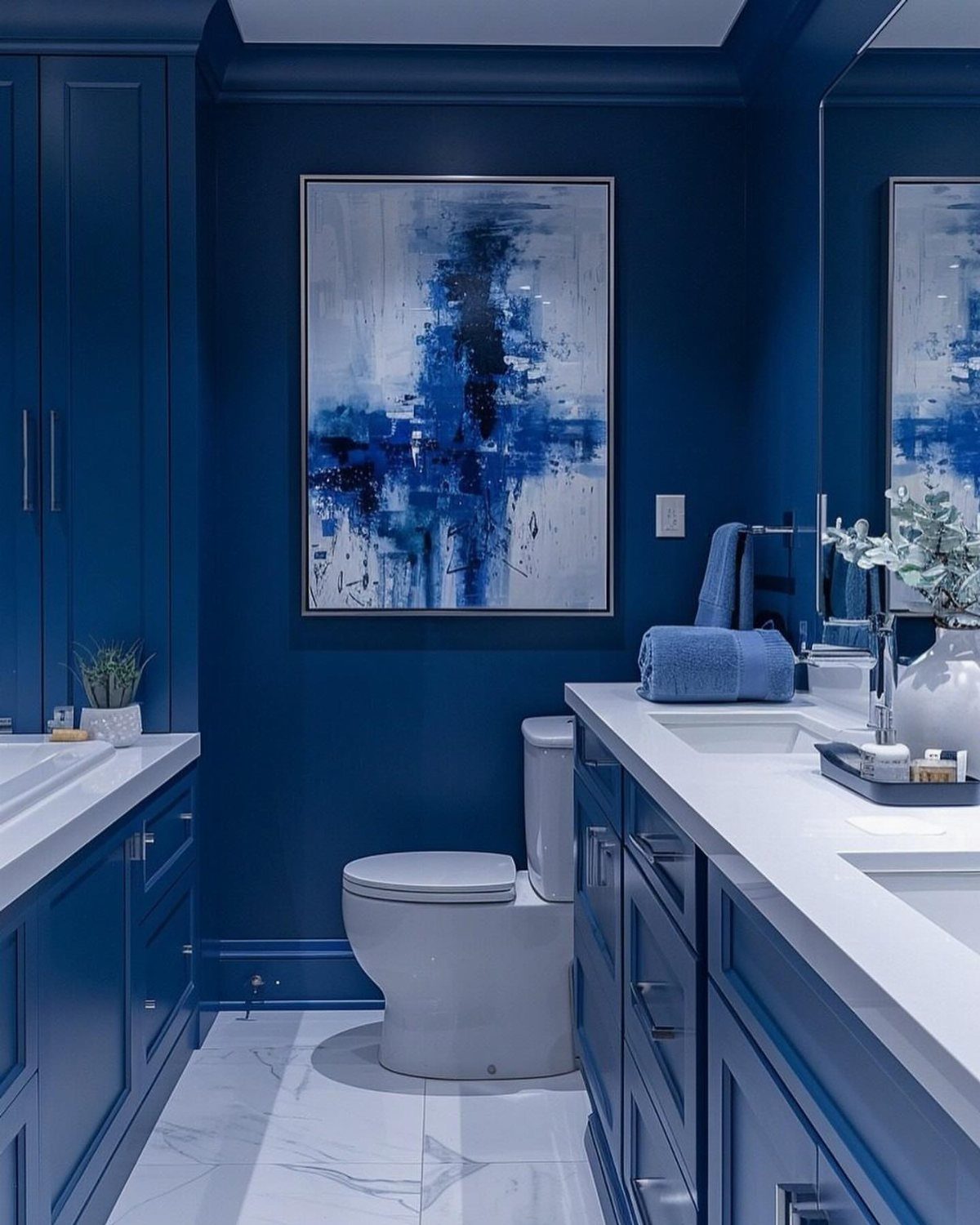 Navy blue bathroom with matching cabinets, white marble floors, and abstract art.