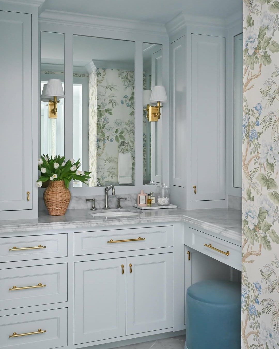 Powder blue bathroom cabinetry with gold hardware and white marble countertops.