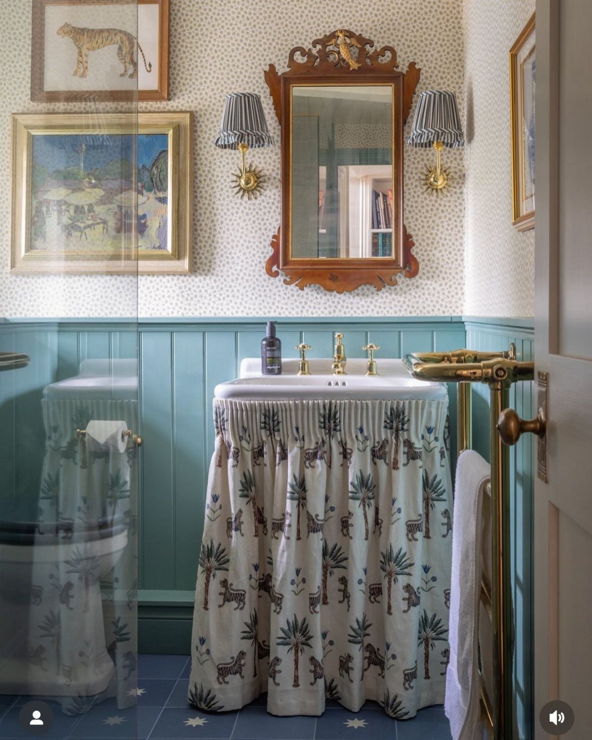 White sink with a patterned fabric skirt in a blue themed bathroom.