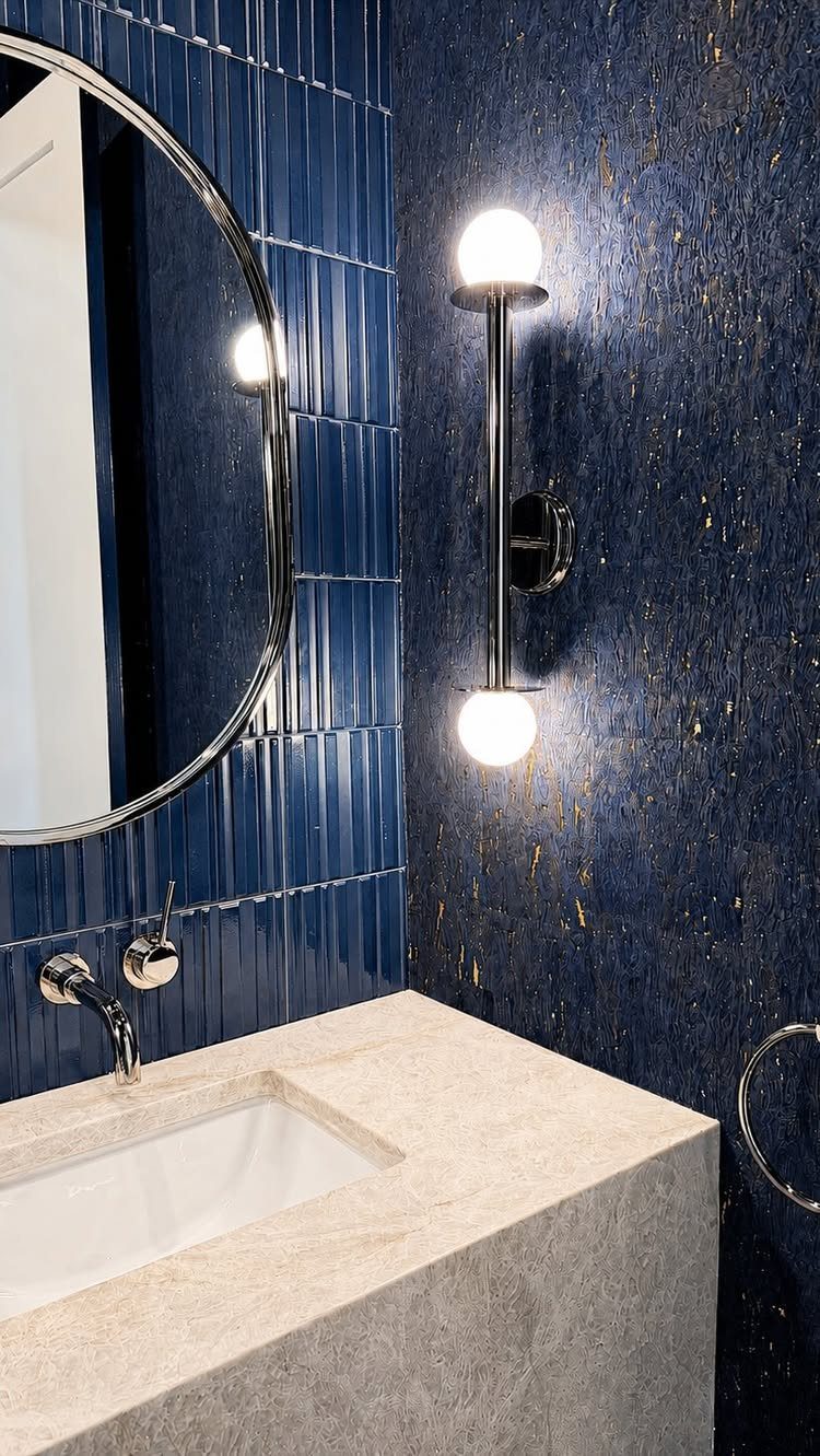 Dark blue vertical subway tiles and textured navy wall with stone vanity sink.