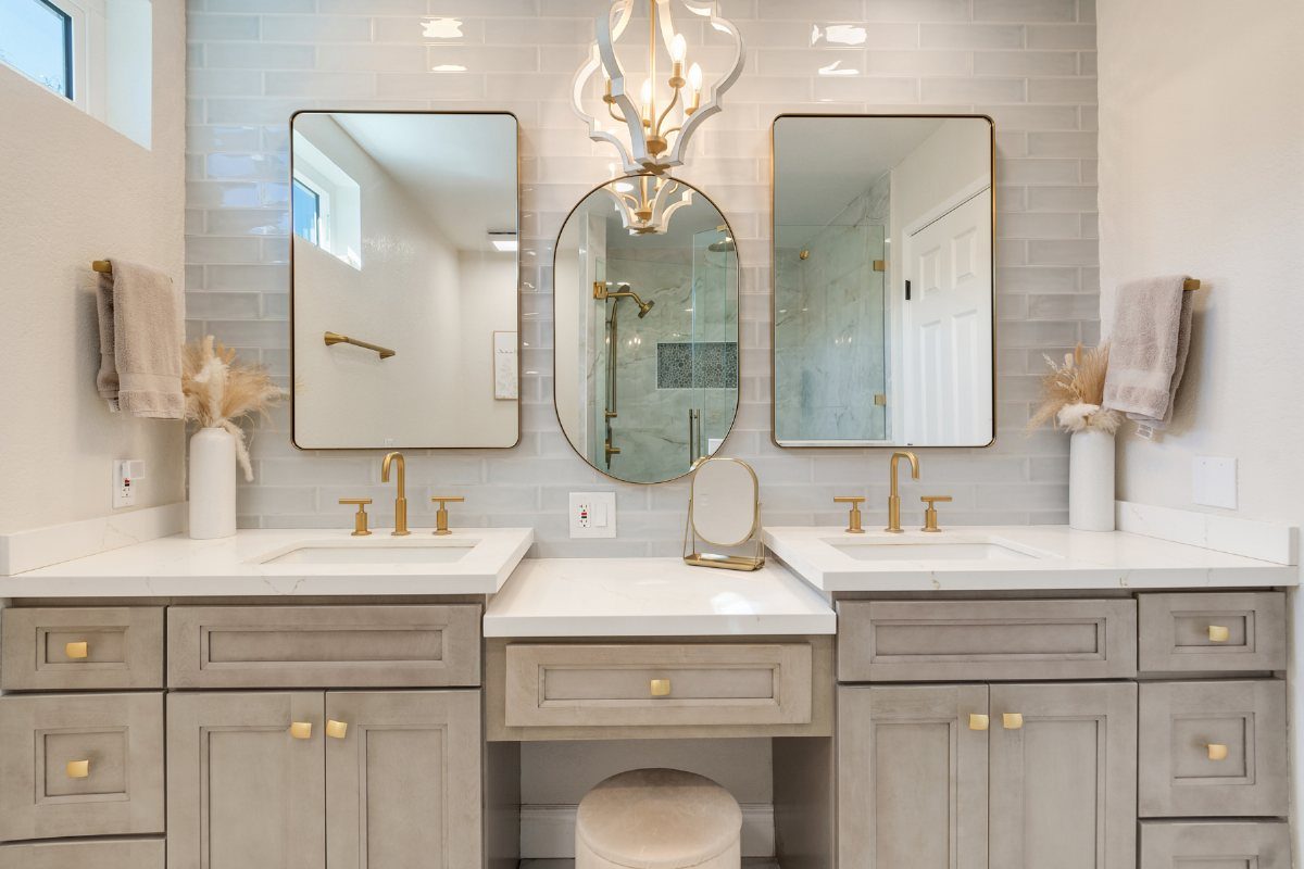 Grey double sink bathroom vanity with white marble top and gold hardware.