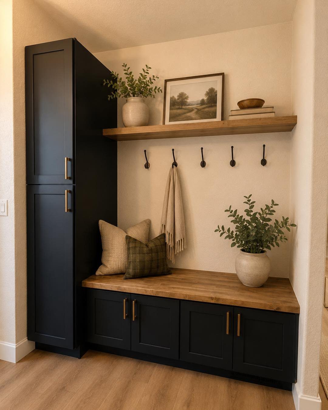 Black storage bench with wooden top, wall hooks, and a tall black cabinet.