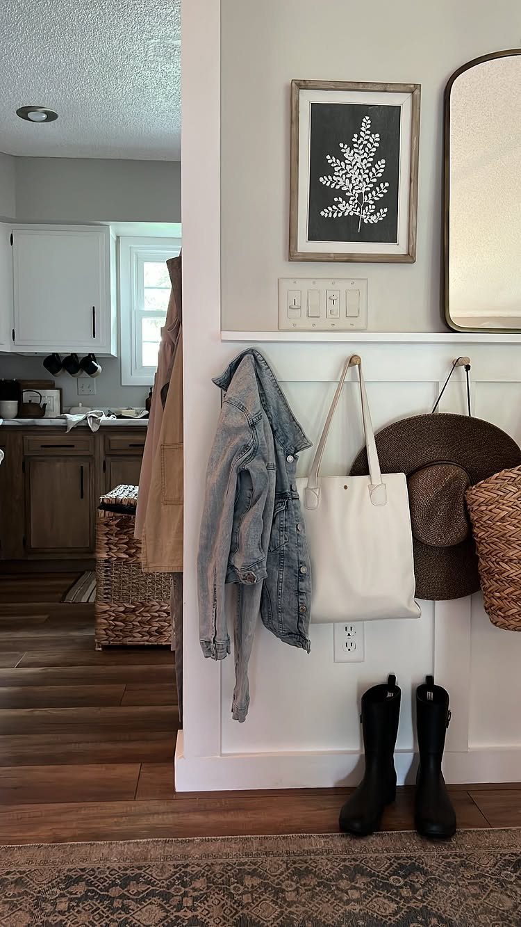 Patterned brown rug in an entryway with hooks, bags, and black boots.