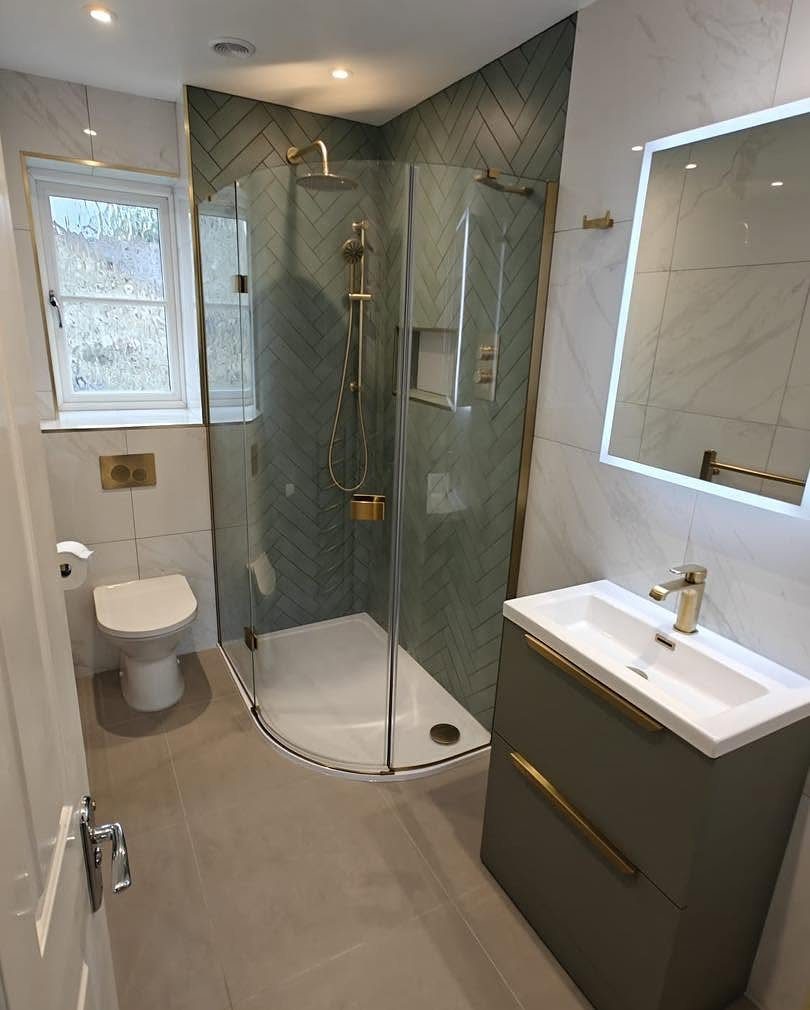 Curved glass corner shower with gold fixtures in a modern grey bathroom