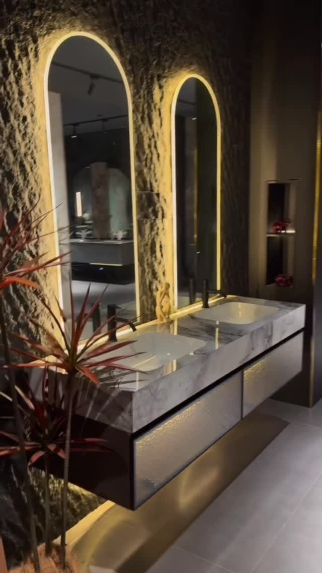 Double sink vanity with marble countertop and two arched gold-framed mirrors.