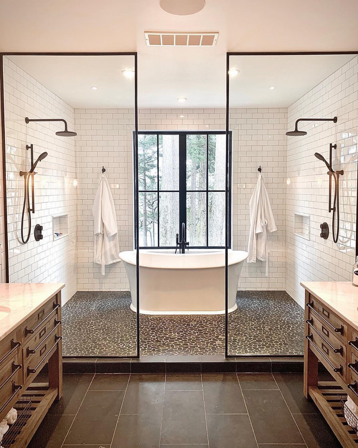 Freestanding bathtub and dual walk-in showers in a modern wet room bathroom design.