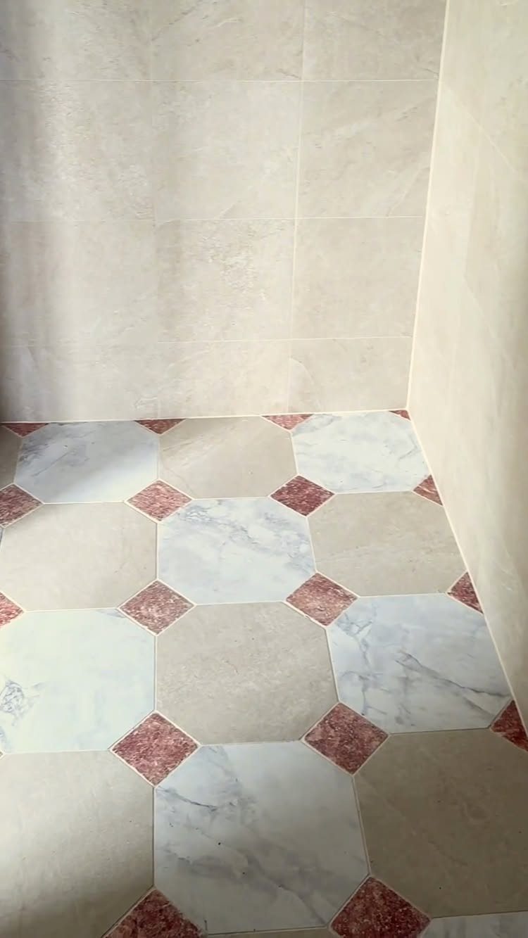 Octagonal white and beige floor tiles with small red diamond accents in a bathroom.
