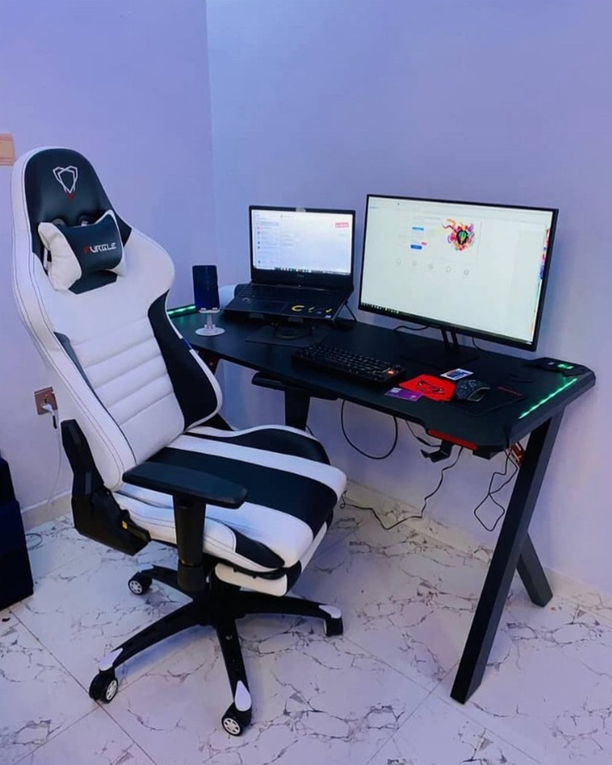 White and black ergonomic gaming chair at a dual monitor computer desk setup.