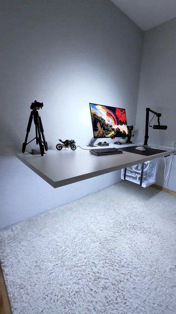 Floating white gaming desk with monitor and PC tower against a grey wall