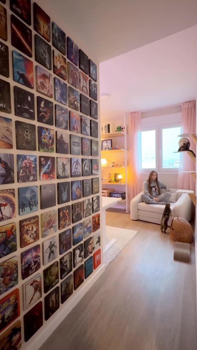 Wall of gaming posters in a small room with a person on a beanbag.