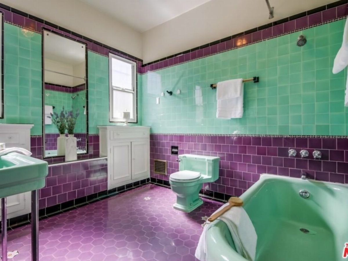 Mint green bathroom with purple hexagonal floor tiles and a vintage bathtub.