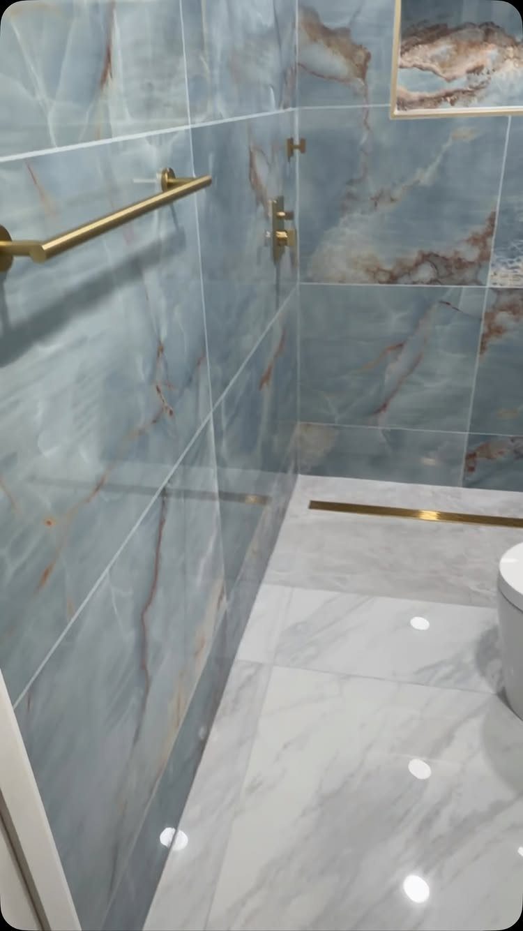 Blue marbled tiles covering bathroom walls from floor to ceiling with gold fixtures.