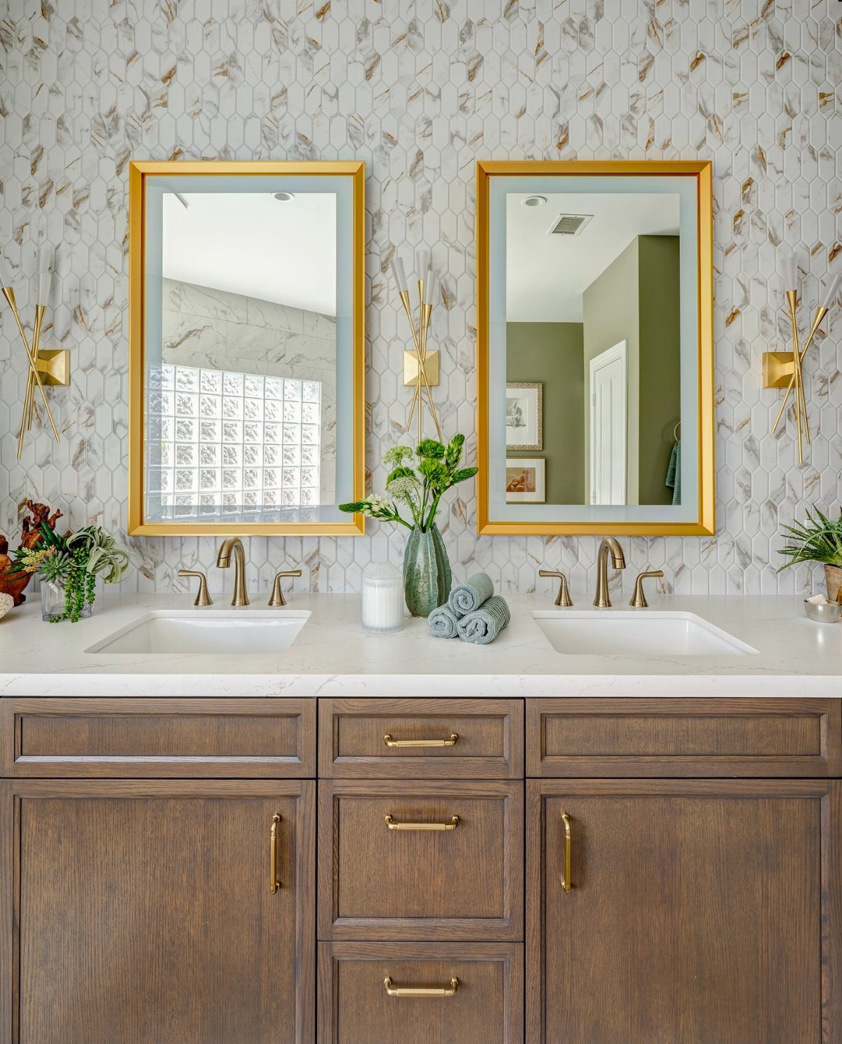 Bathroom vanity with gold mirrors against a wall of hexagonal mosaic tiles.