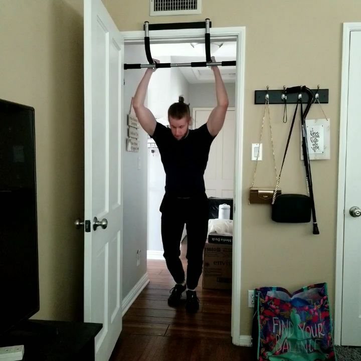 Man performing pull-ups on a doorway bar inside a home apartment setting.