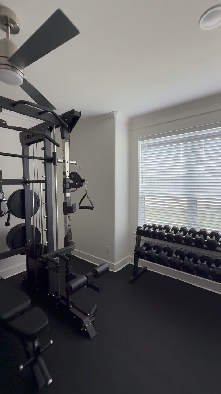 Home gym setup with a multi-functional weight machine and dumbbells in a room.