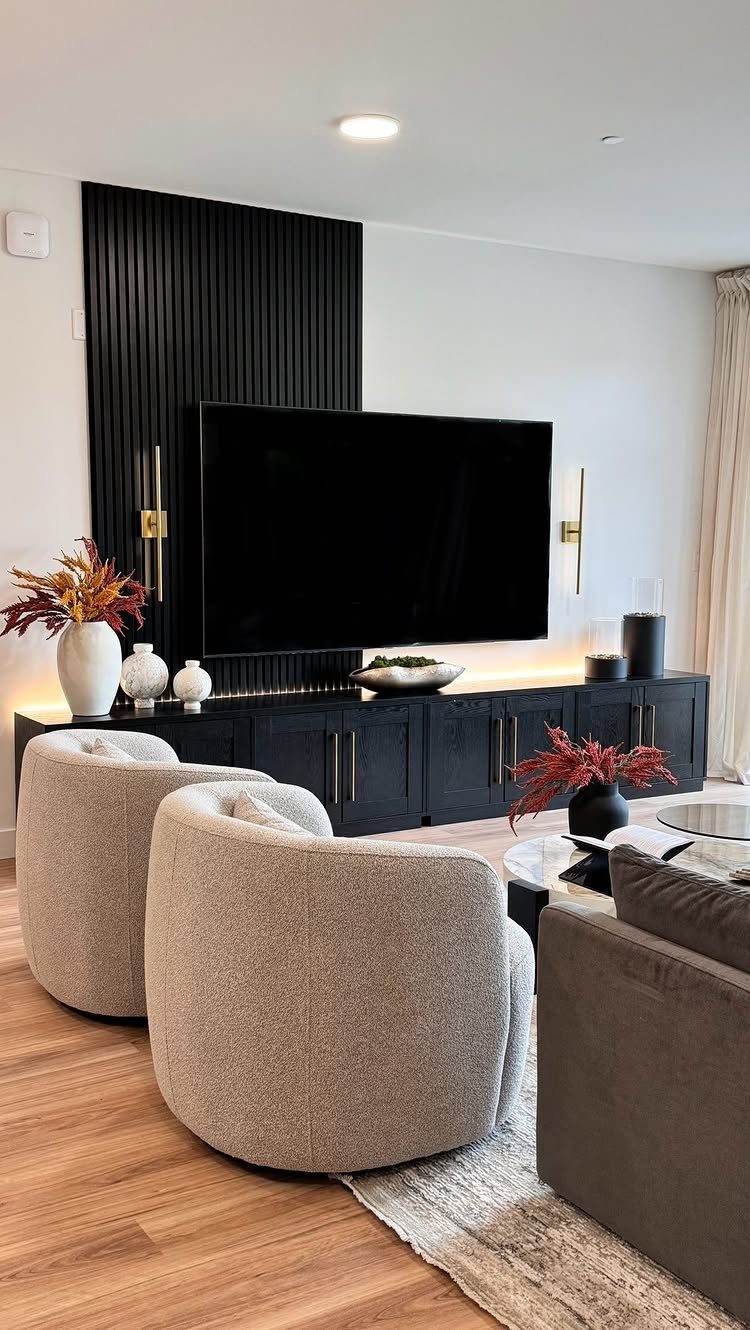 Modern living room with curved beige chairs, black console, and slatted accent wall.