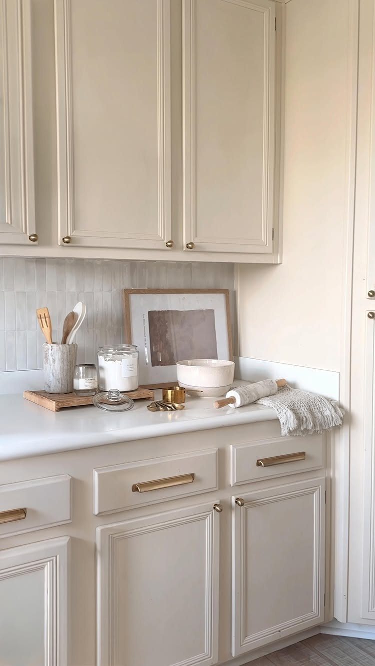 Cream kitchen cabinets and white countertops with a tiled backsplash and decorative accessories.