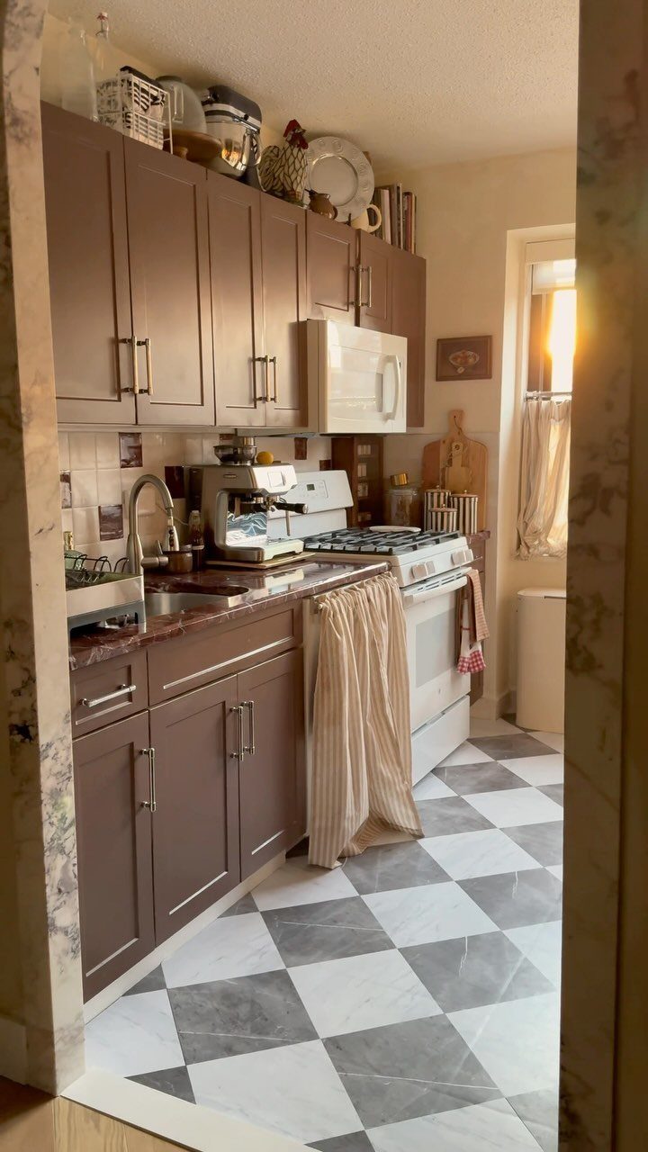 Small kitchen with brown cabinets and a grey and white checkered floor.
