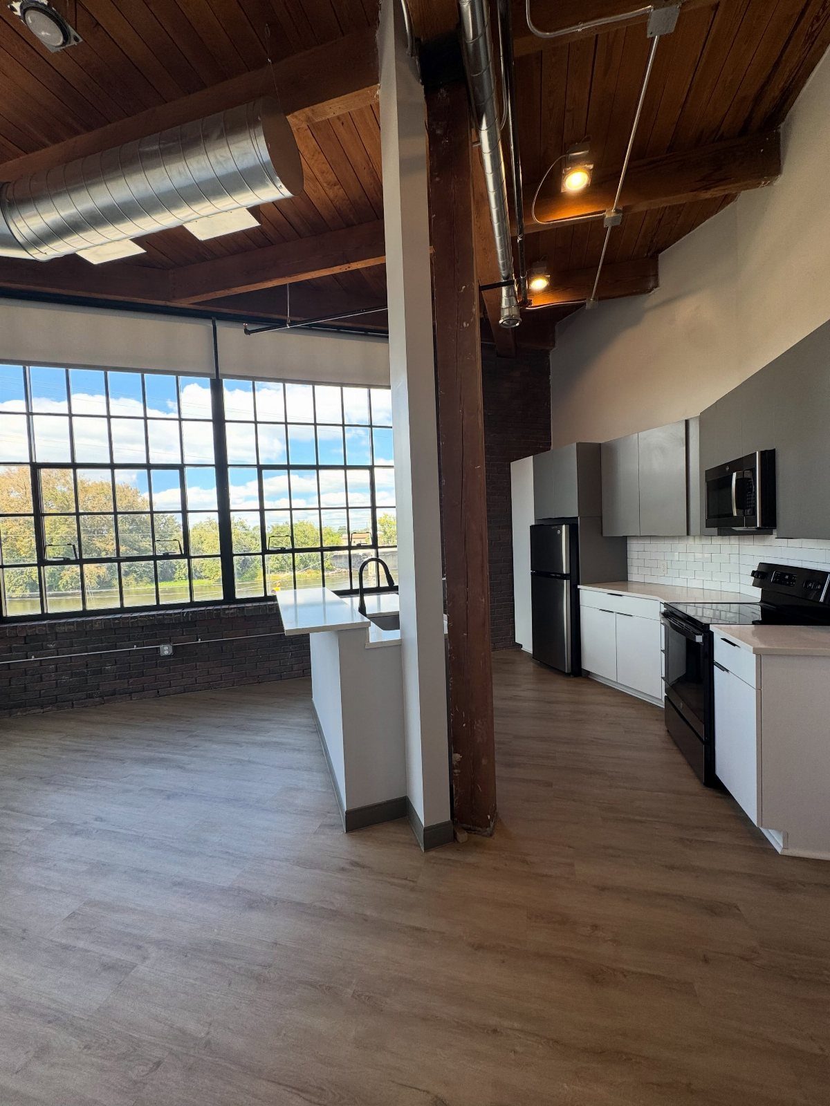Loft apartment interior with exposed brick, wooden ceiling beams, and a modern kitchen.