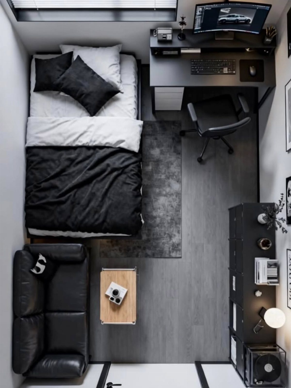 Small studio apartment with black furniture, a bed, and a workspace in monochrome.