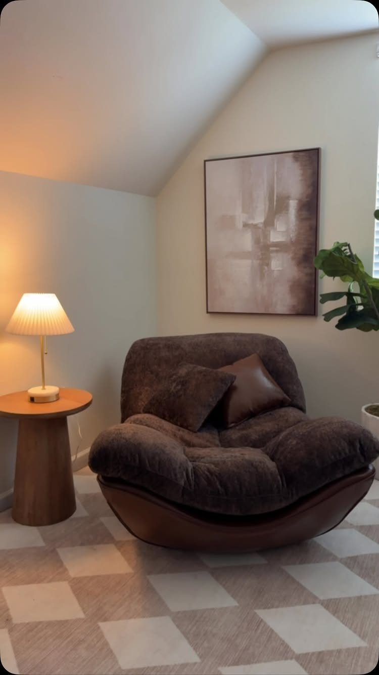 Brown plush armchair with a side table and lamp in a cozy corner
