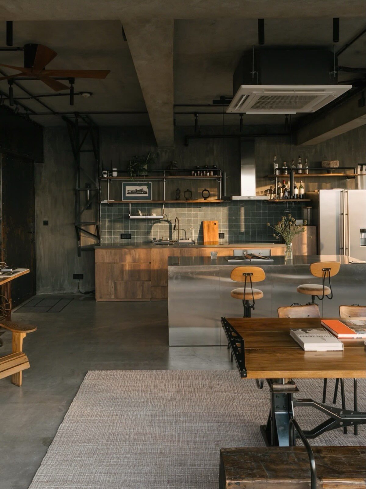 Stainless steel kitchen island in an industrial studio apartment with concrete walls.