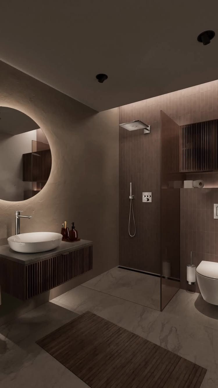 Modern bathroom featuring a backlit round mirror and warm accent lighting on walls.