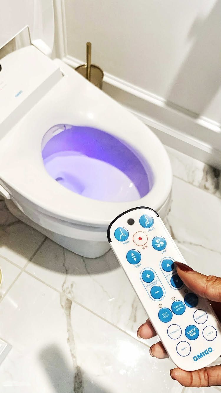 Smart toilet with purple interior light and a handheld remote control on marble floor