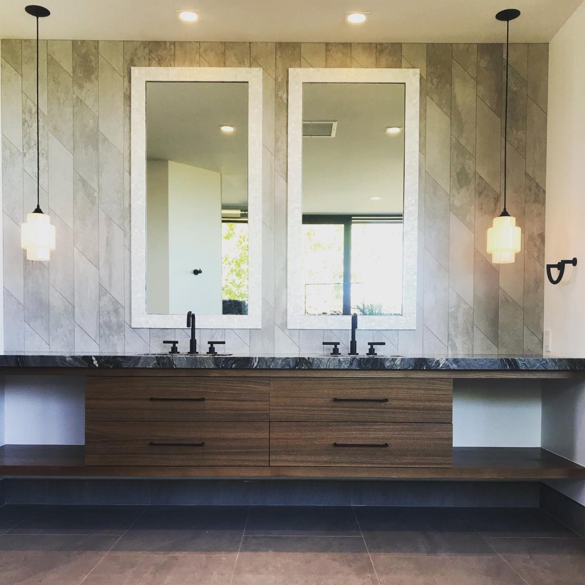 Wooden floating double vanity with marble countertop and two white-framed mirrors in bathroom