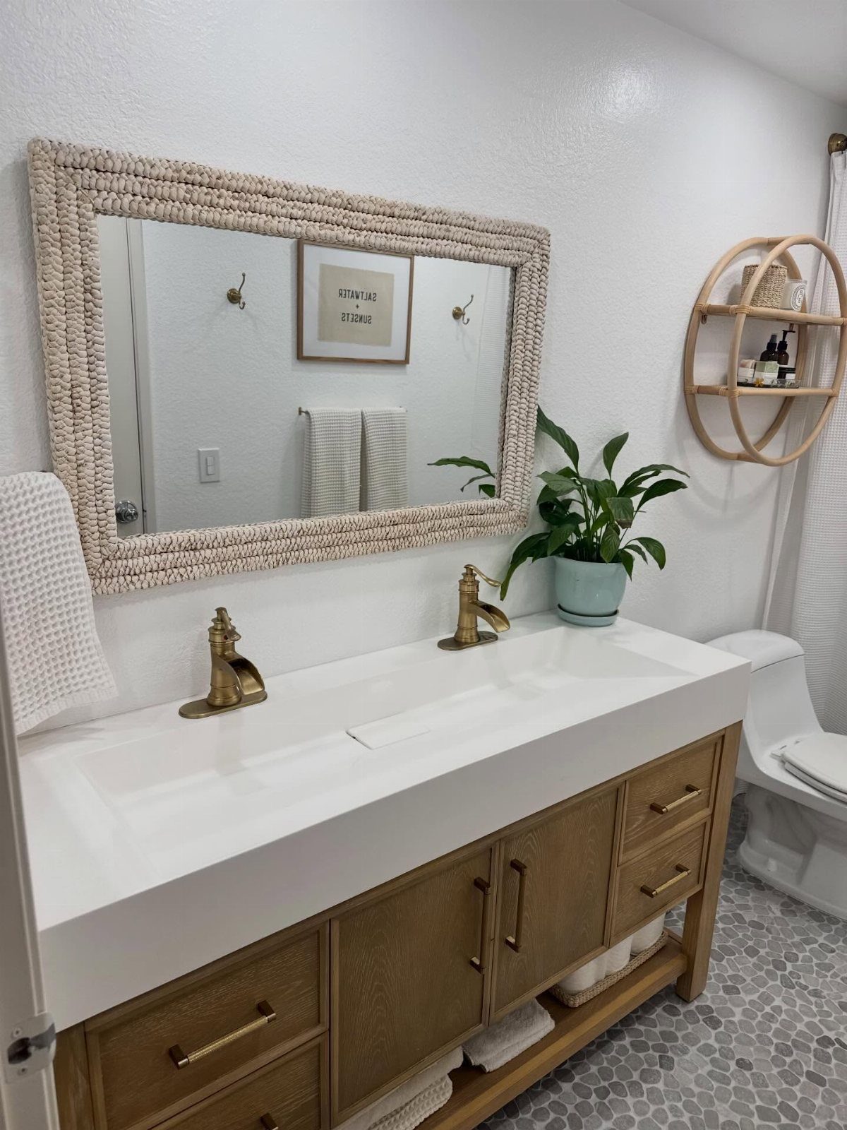 Large rectangular mirror with textured frame above a white bathroom vanity and sink.